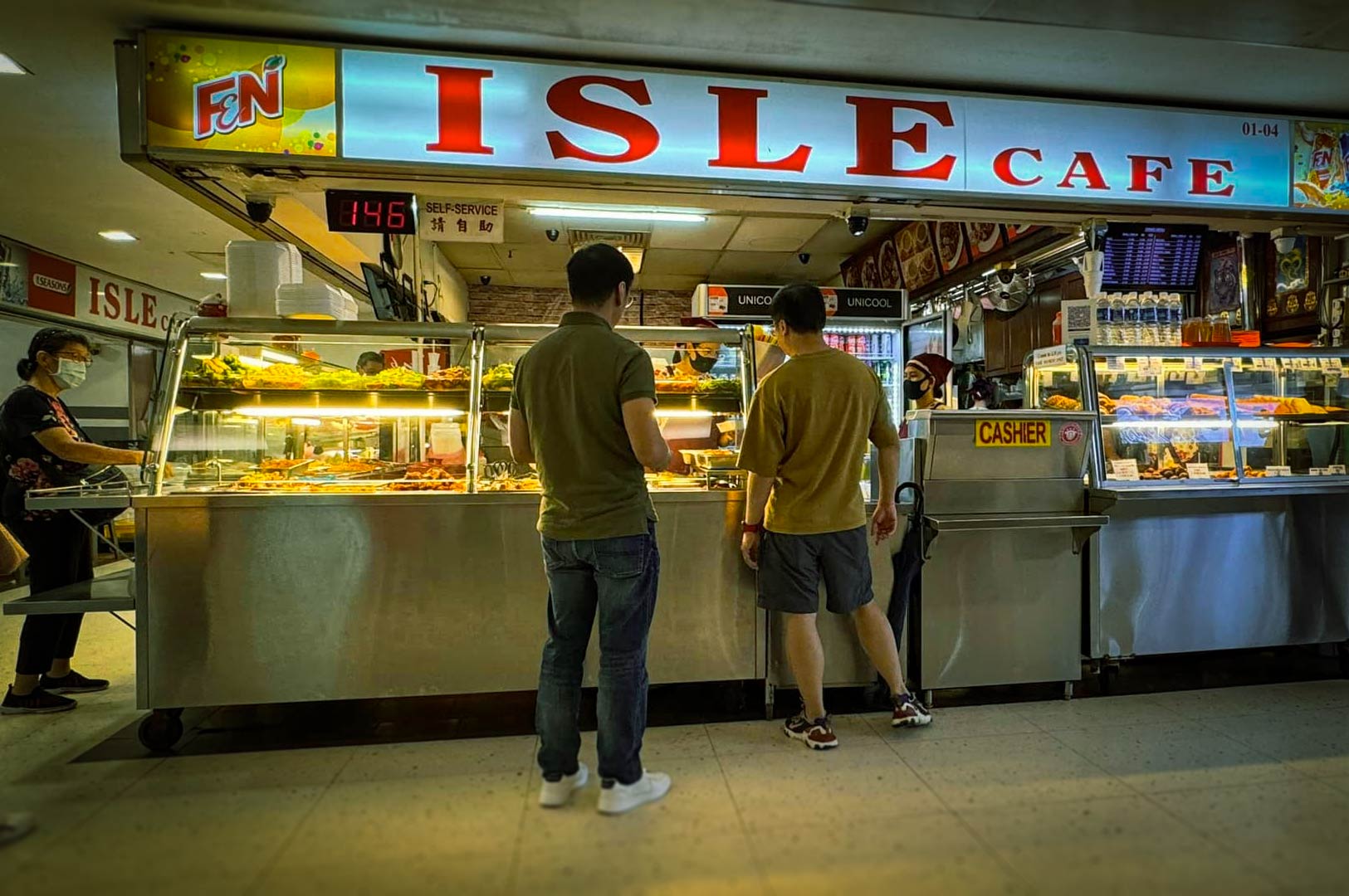 Wide shot of Isle Cafe stall with customers selecting meals from display.
