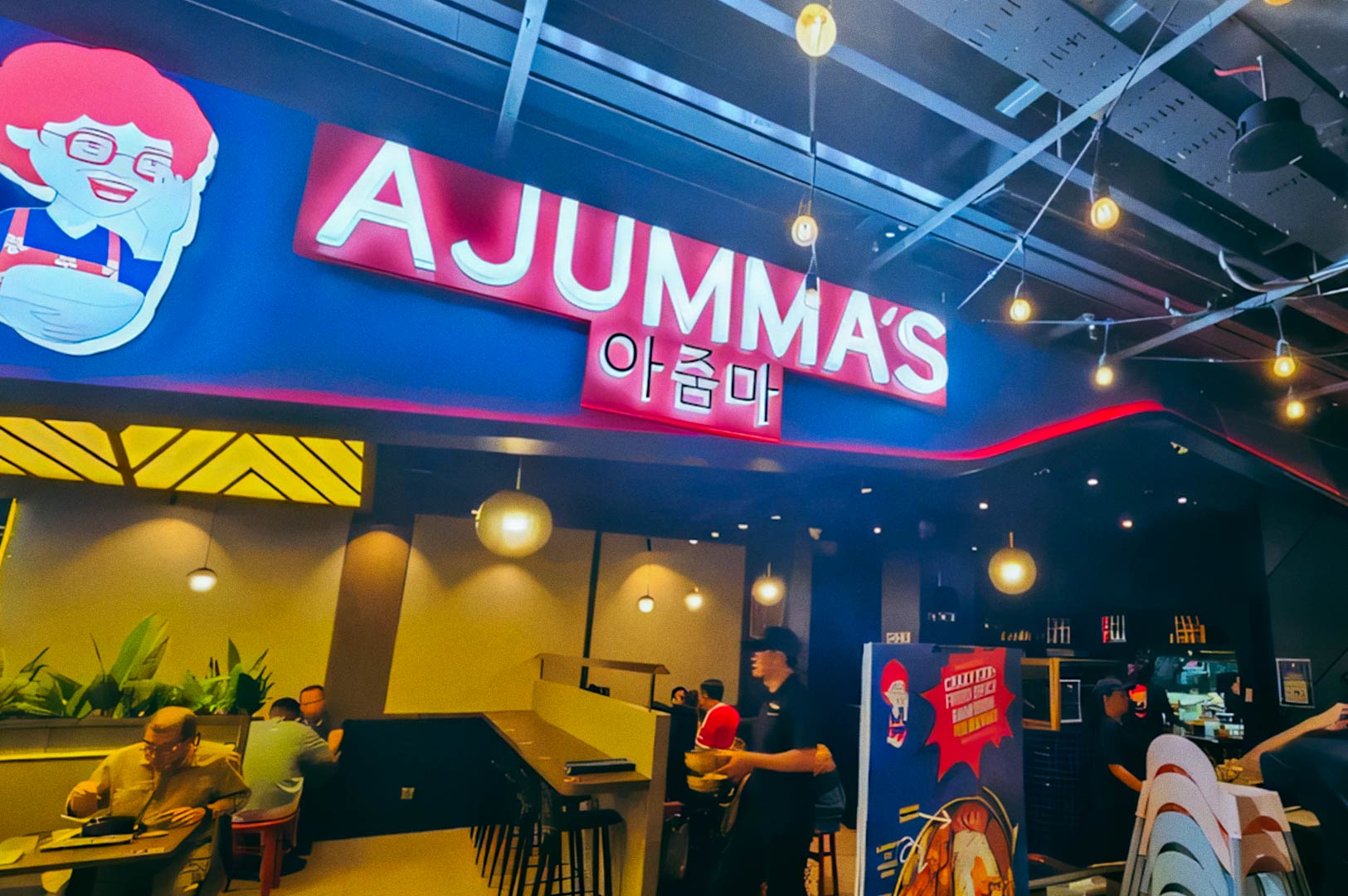 Ajumma’s Korean restaurant interior with illuminated signage.