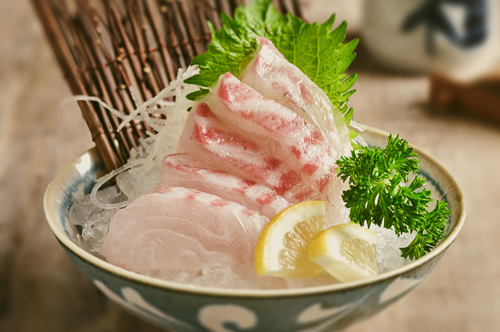 Beautifully plated Ringo Madai Sashimi with marbled raw fish slices fanned on crushed ice, garnished with daikon, shiso, parsley, and lemon wedges.