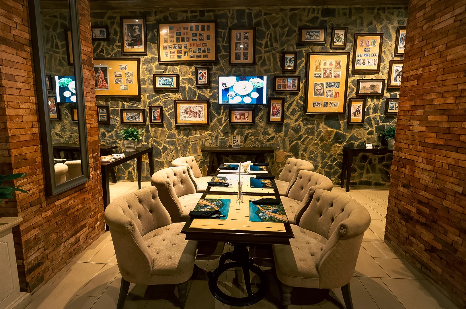 Wide‑angle interior shot of a stylish restaurant dining room with upholstered chairs, neatly set tables, framed wall art, and warm ambient lighting, showcasing upscale restaurant design, cozy seating, and inviting dining ambiance.