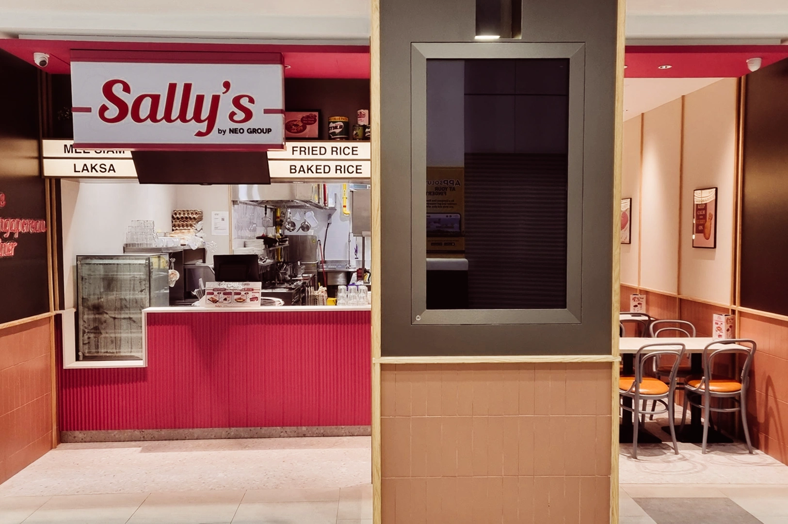 Wide-angle eye-level shot of Sally’s by Neo Group food stall inside a shopping mall, featuring red signage, open kitchen counter, and menu boards offering laksa, fried rice, and baked rice.