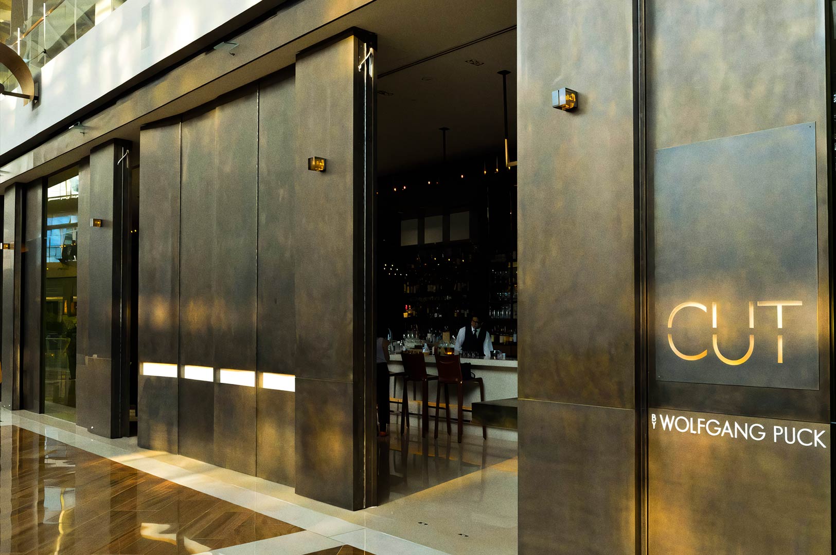 Entrance of a modern fine‑dining restaurant with dark metallic design.