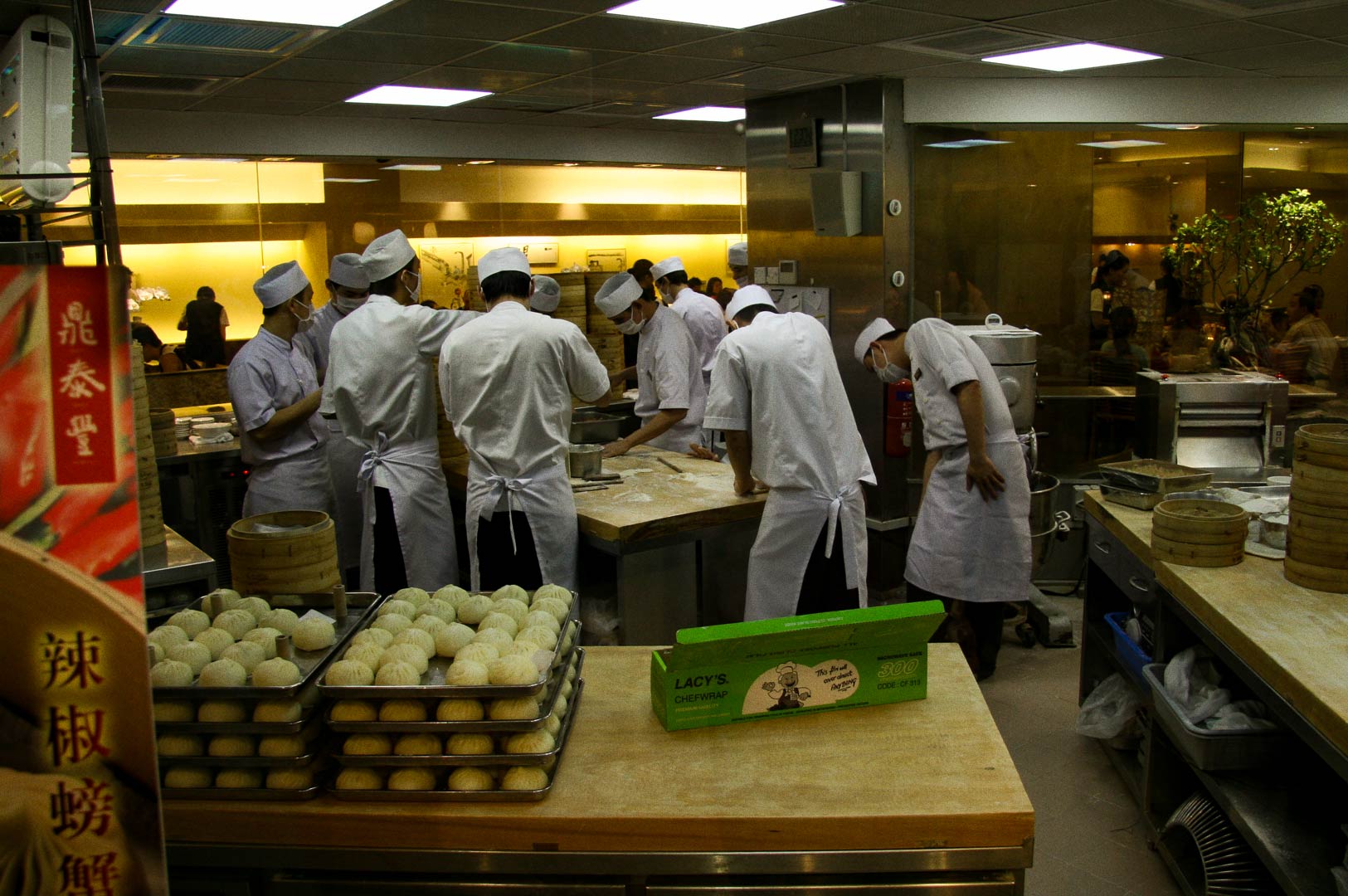 Kitchen staff preparing dumplings at a busy restaurant workstation.