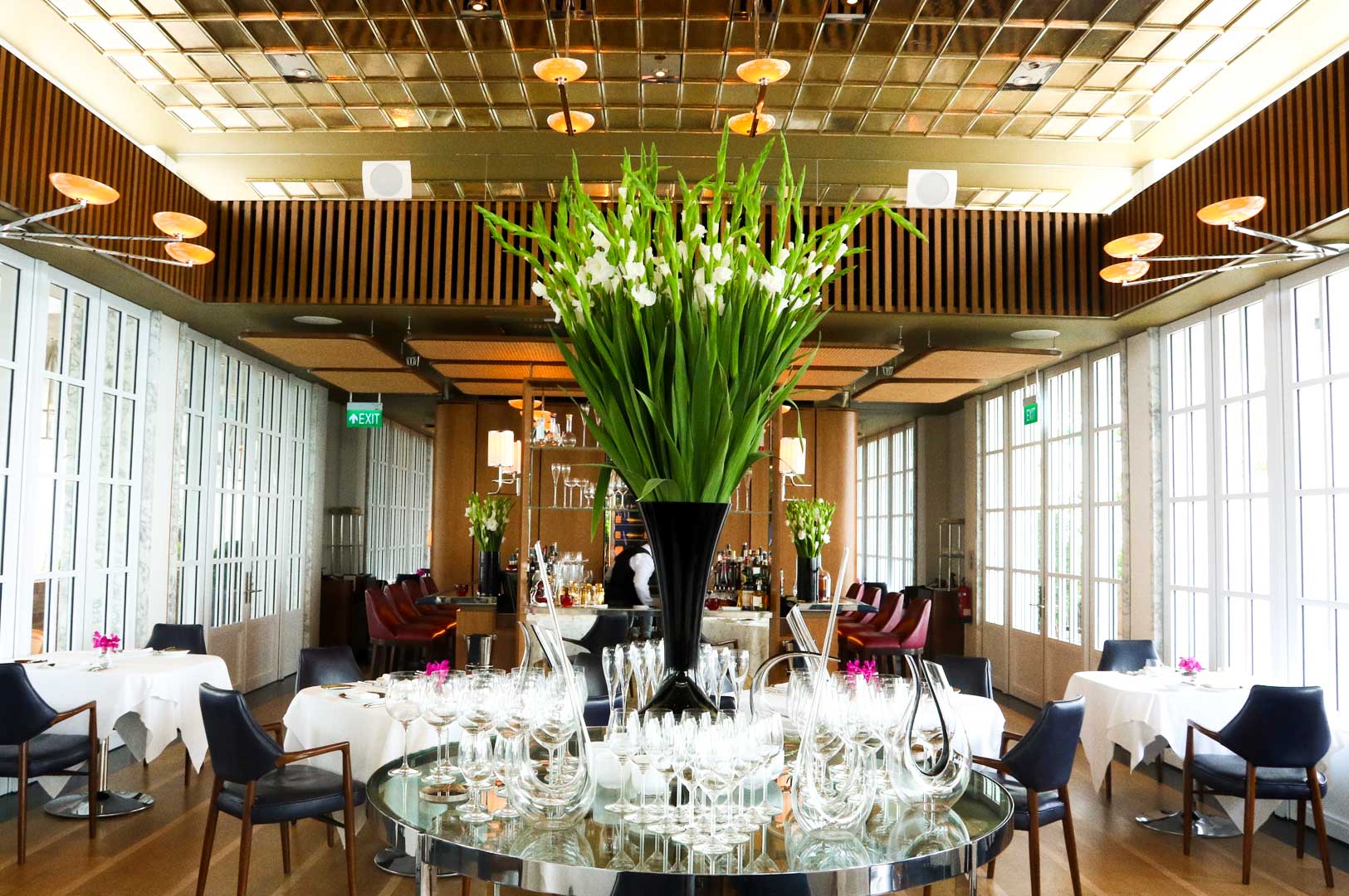 Elegant restaurant interior with large floral centerpiece and glass decor.