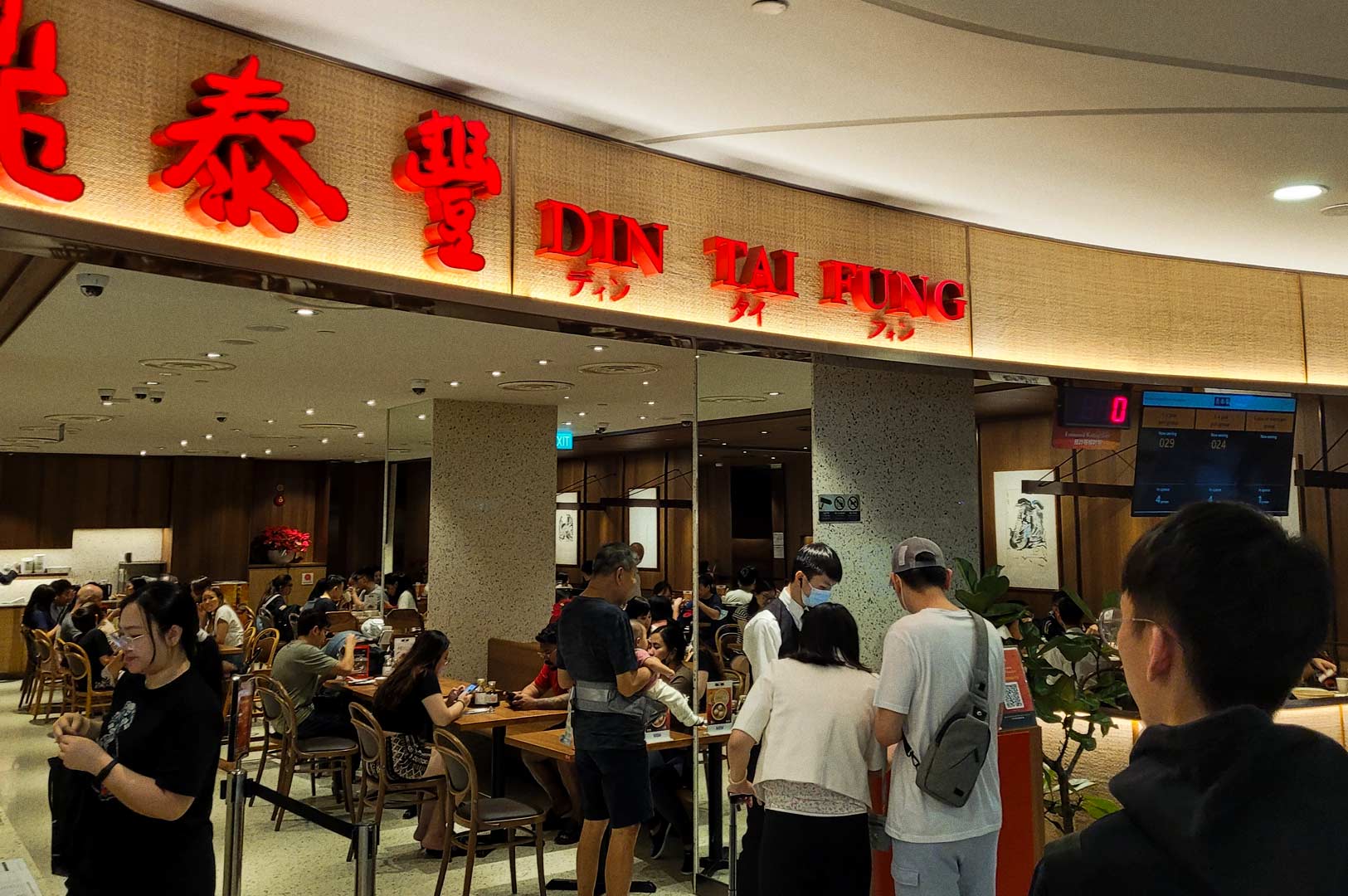 Restaurant entrance with illuminated signage and diners inside.