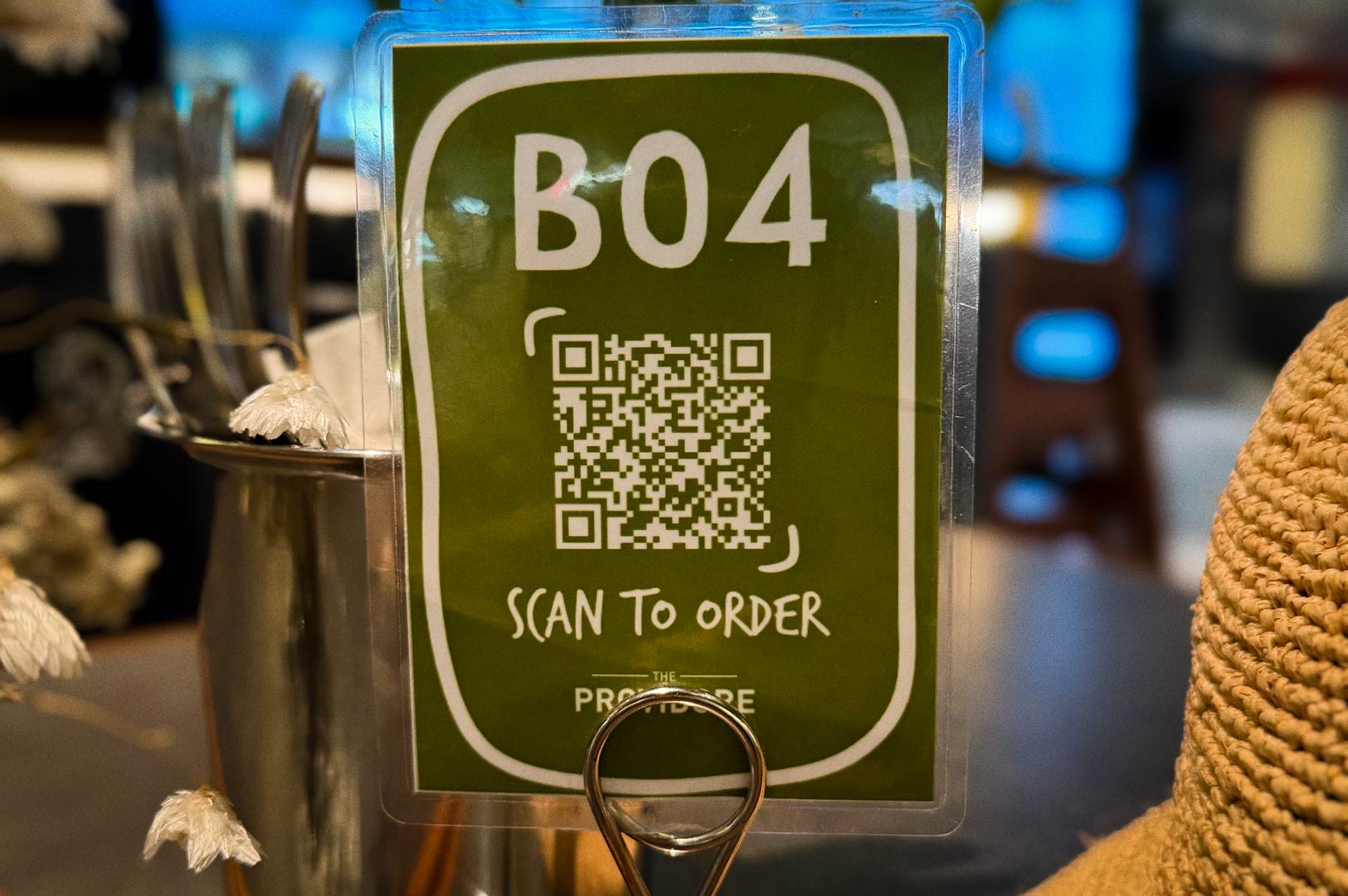A tabletop sign featuring a QR code for scanning to order, placed next to a container holding utensils.