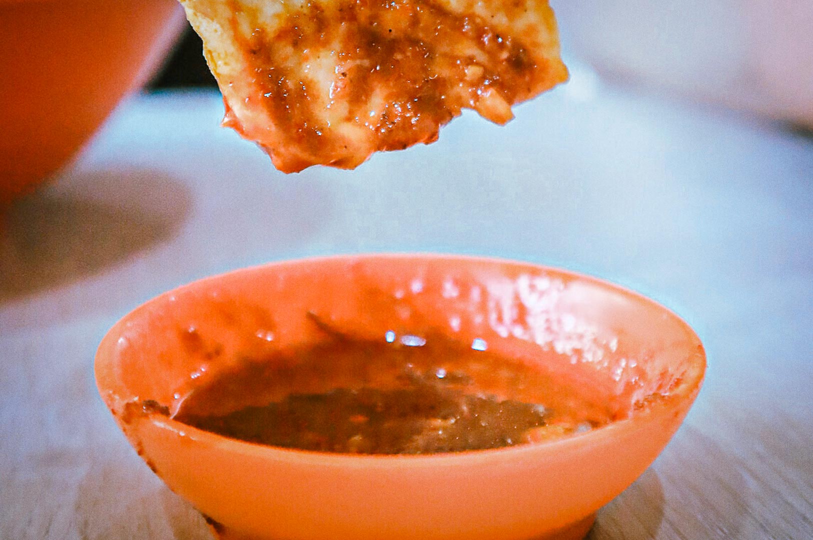 Close-up of tofu dipped in a spicy red sauce.