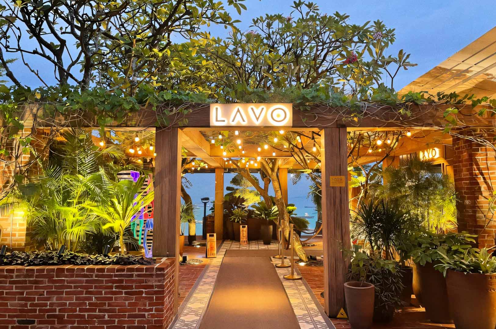 Outdoor restaurant entrance decorated with lights and greenery.