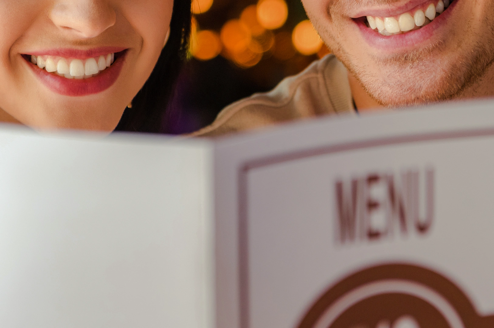 1 Limited-Time Menu Close‑up eye‑level shot of two diners holding and reading a restaurant menu at a table, with warm ambient lighting and a softly blurred background suggesting a cozy dining atmosphere.