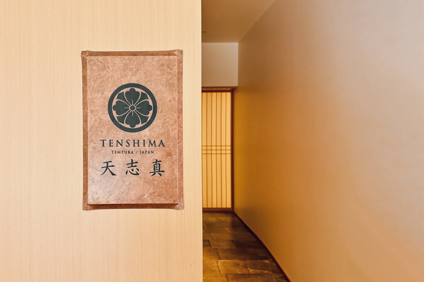 1 Tenshima Millenia Walk Eye-level shot of the Tenshima tempura restaurant sign along a minimalist Japanese corridor at Millenia Walk, featuring soft lighting and traditional design.