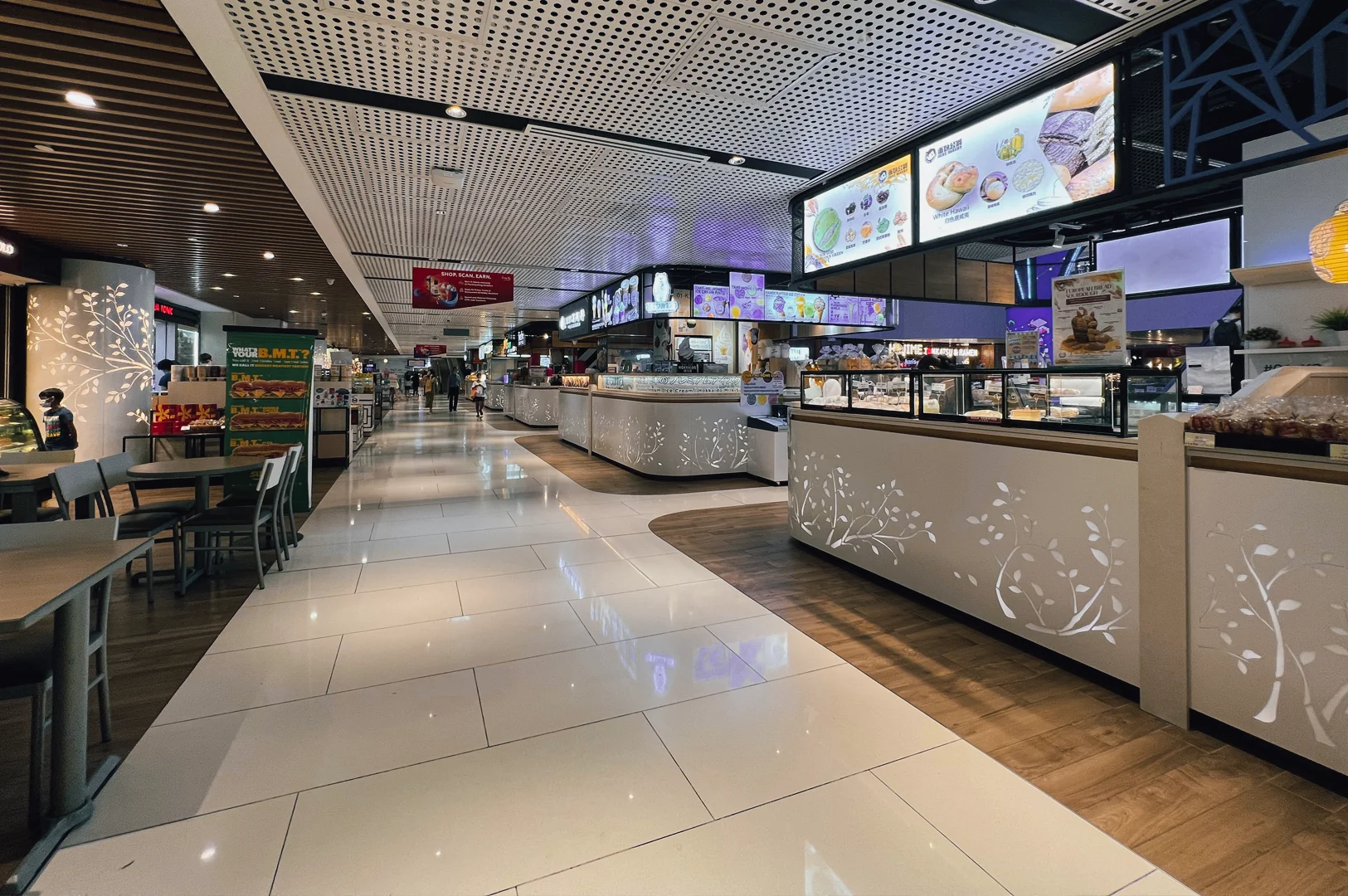 2 How We Found the Best Mall for Foodies Wide-angle eye-level view of a clean, contemporary mall food court with multiple food stalls, digital menu boards, seating area, and bright lighting, showcasing an organized food hall designed for food lovers.