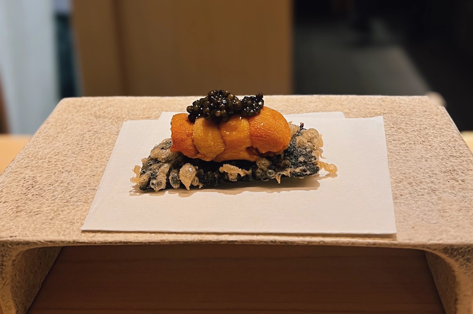 4 Tenshima Millenia Walk Close-up, straight-on shot of sea urchin tempura topped with caviar, served on handmade paper at Tenshima omakase restaurant, Millenia Walk.