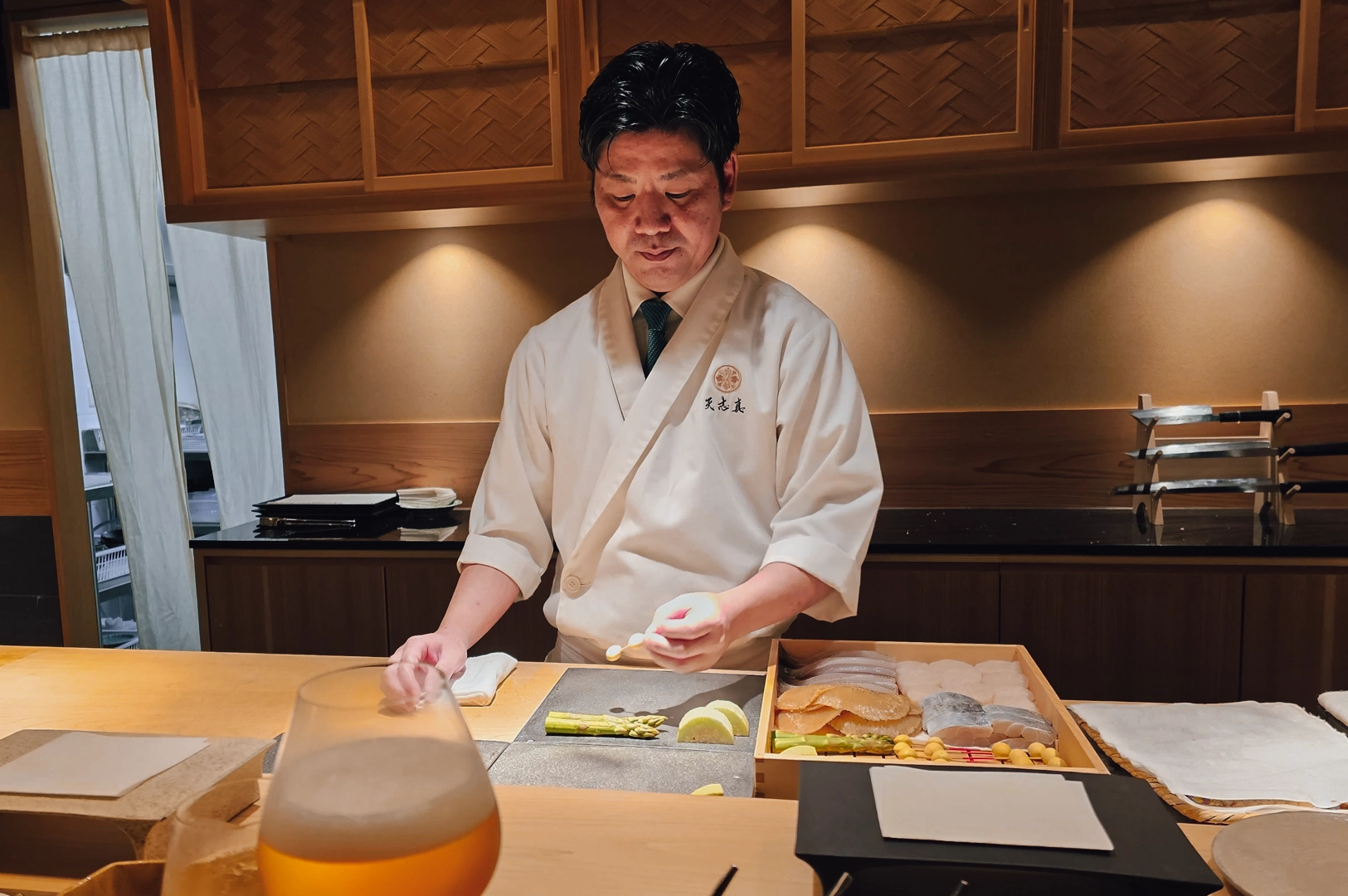 5 Tenshima Millenia Walk Eye-level medium shot of a Japanese tempura chef preparing an omakase course at Tenshima, Millenia Walk, with fresh ingredients arranged at a wooden counter in an intimate dining setting.