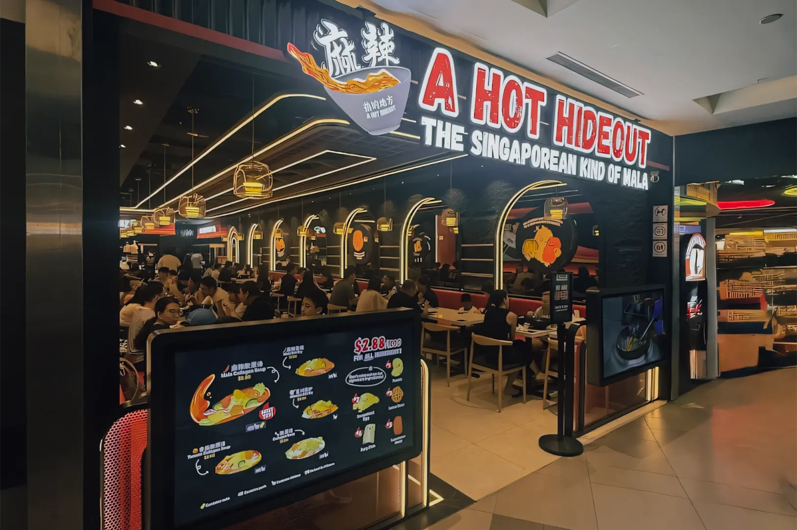 Wide-angle eye-level shot of A Hot Hideout NEX restaurant exterior at Serangoon Mall, featuring bold signage, illuminated menu boards, and a busy indoor dining area known for Singapore-style mala hotpot.