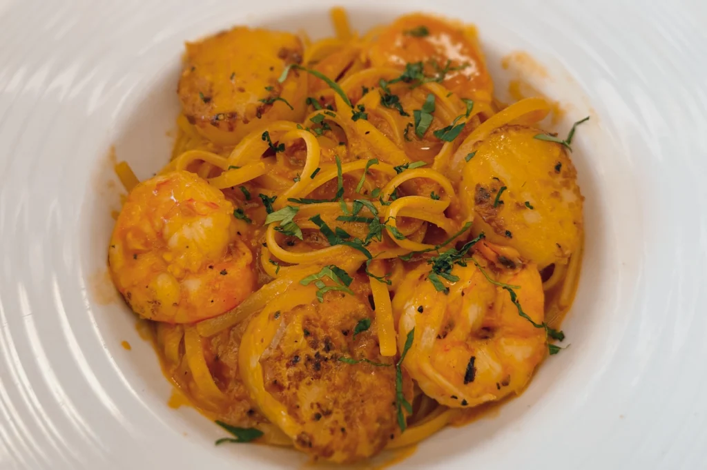 Overhead shot of seared scallop and prawn pasta with creamy orange sauce at The Marmalade Pantry, highlighting fresh seafood, caramelized scallops, and herb-garnished linguine.
