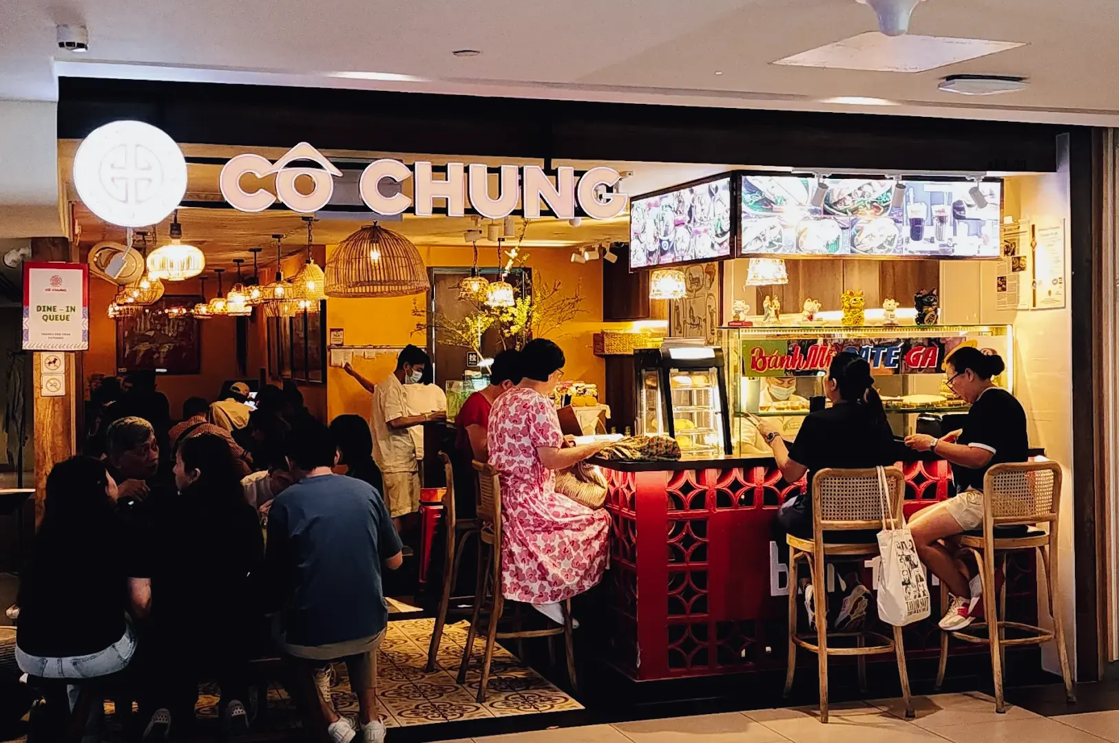 Eye-level wide shot of Co Chung Vietnamese restaurant at Plaza Singapura, showing a busy dining crowd enjoying pho and casual meals along Orchard Road Singapore’s popular food scene