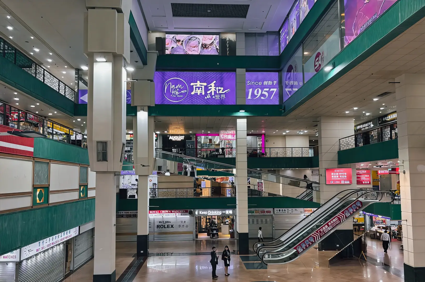 Eye-level wide interior shot of People’s Park Complex city room atrium with escalators, multi-level retail shops, and signage, highlighting bustling Chinatown Singapore shopping centre and hawker culture environment