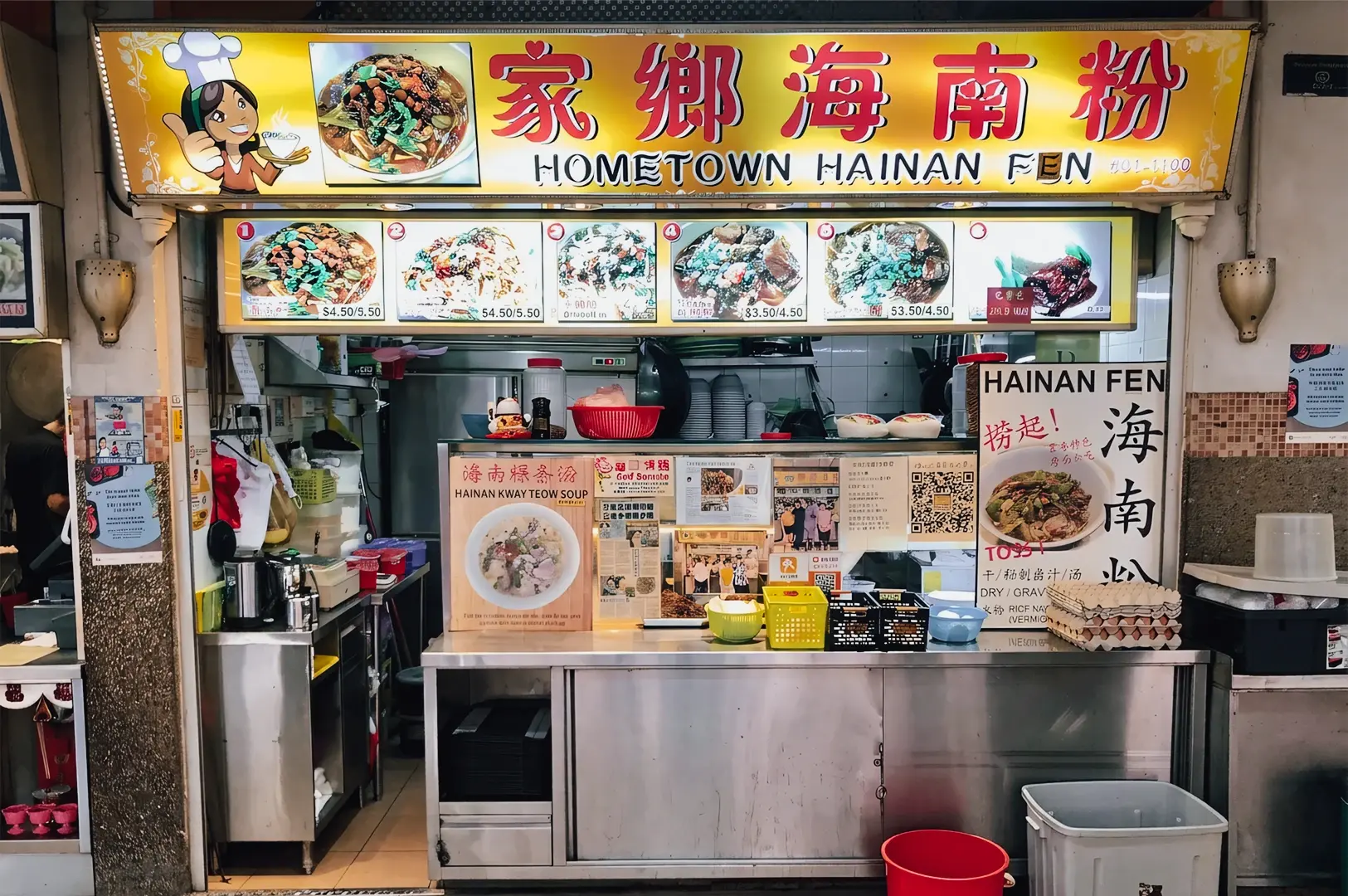 Eye-level frontal shot of Hometown Hainan Fen hawker stall in People’s Park Complex food centre Singapore, with menu signage, traditional dishes, and stainless steel counter setup
