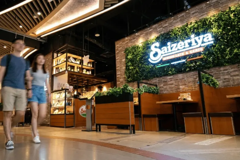 Shoppers walking past the vibrant and inviting exterior of the Saizeriya Italian restaurant located inside the Changi City Point mall.