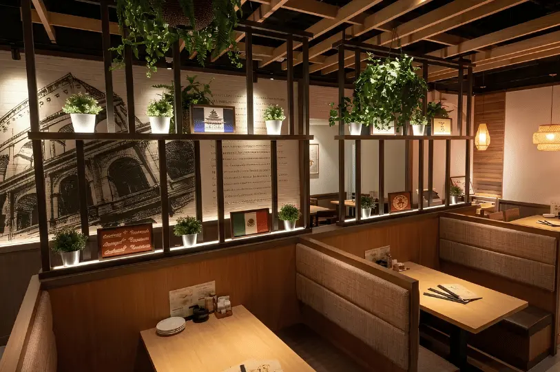 Cozy booth seating inside the Saizeriya Changi City Point restaurant, decorated with warm lighting, hanging plants, and Italian-themed wall art.