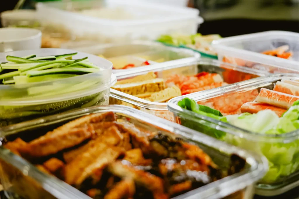 Packed meals of varying fresh and healthy contents placed in glass containers.