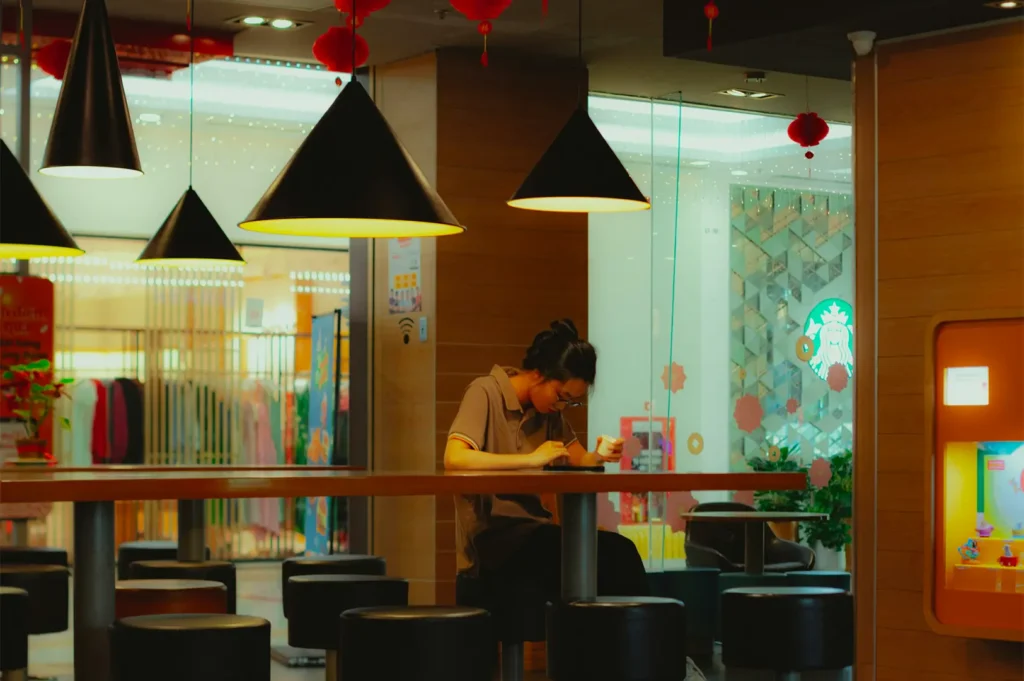 A woman on her phone dining alone in a warmly lit restaurant.