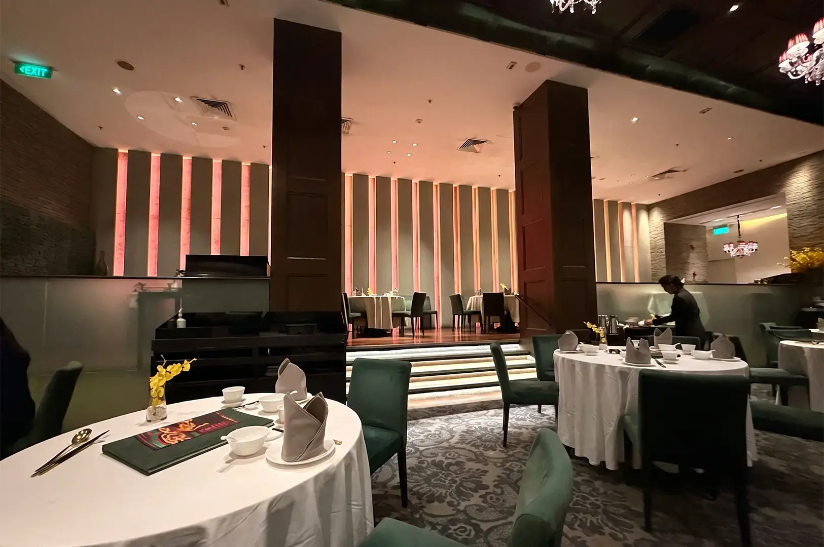 Crystal Jade Golden Palace interior with white and black tables and chairs and brown pillars and ceiling, accented with a dim warm lighting.