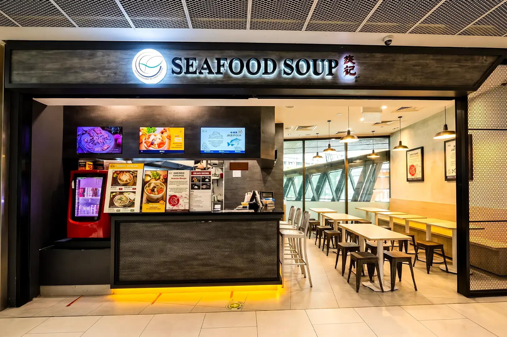 Yan Ji store exterior with its huge open space showing empty chairs and tables and the counter filled with promotional materials with the backlit black and white logo signage at the top.
