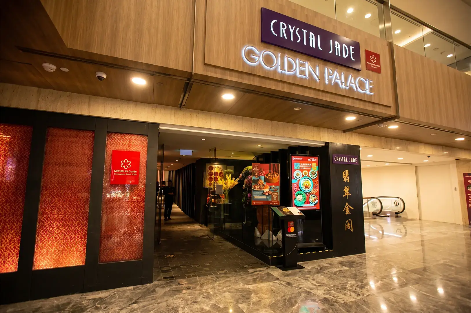Crystal Jade Golden Palace exterior with its logo signage lightly illuminated the upper walls and red and black panels along the open main entrance.