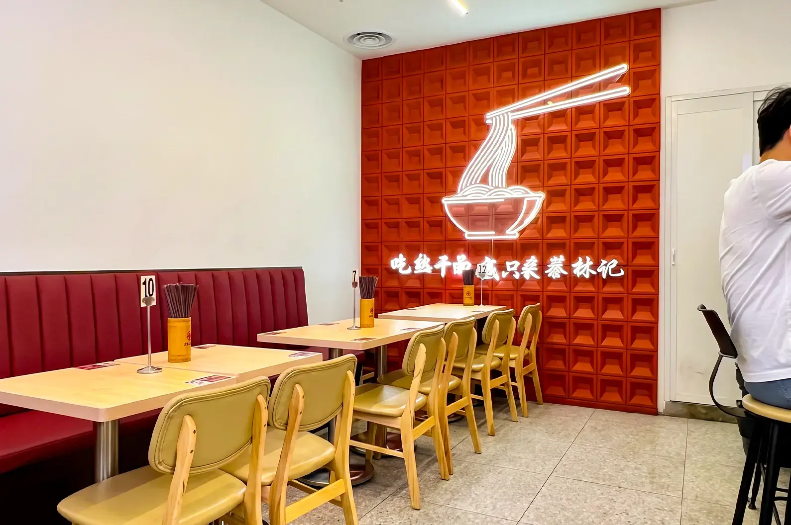 Cai Lin Ji at Jurong Point store interior with a cup noodle wall mural beside empty wooden chairs and tables.