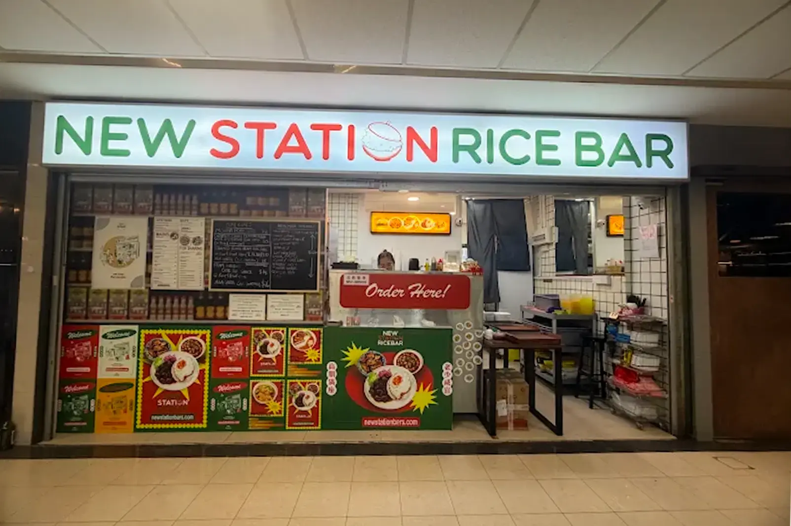 New Station Rice Bar exterior at Fortune Centre with its green and red minimalist logo signage brightly lit above and its menu posters displayed in front
