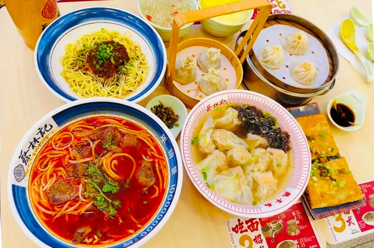 A varity of menu items served at Cai Lin Ji at Jurong Point, including soup, dry noodles, and wonton served on blue and white platters.