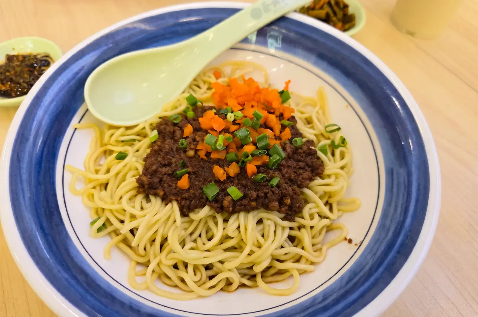 Cai Lin Ji signature Zha Jiang Hot Dry Noodles served in a blue and white bowl.