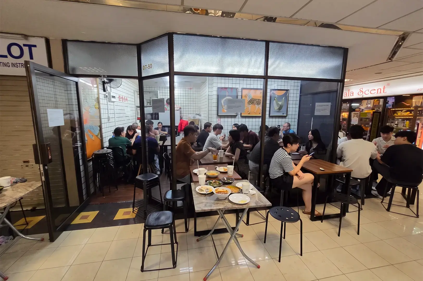 Salted Egg Pork Rice: exterior dining area with a few people eating  inside and outside the place on brown and black tables and chairs.