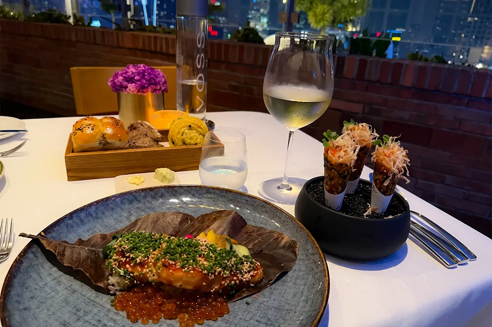 A table with served dishes including Spago Dining Room's Big Eye Tuna Tartare Cones and Hand Cut Agnolotti and Honey Miso Broiled Black Cod.