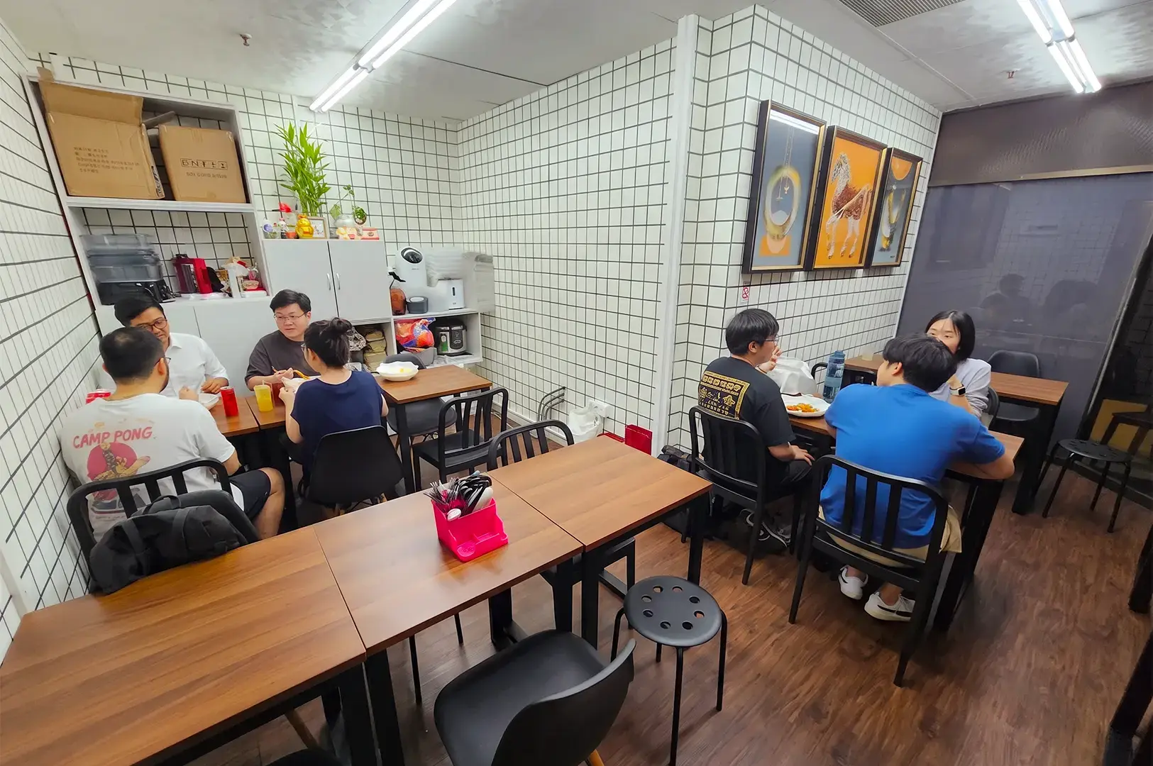 New Station Rice Bar interior with a few tables and chairs occupied by dining customers in a small intimate space surrounded by white tiled walls.